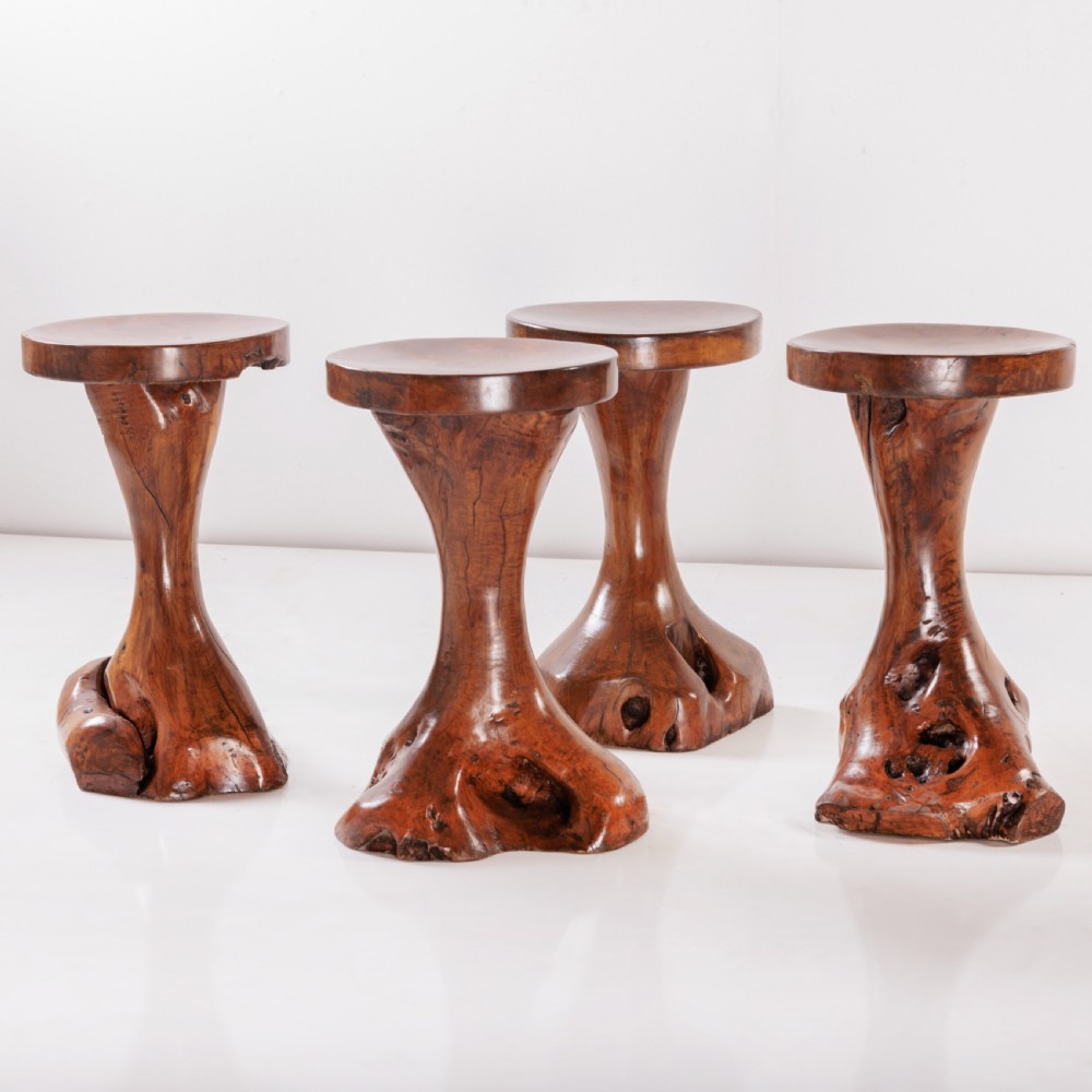 A round olive wood table with a natural tree root pedestal base surrounded by four matching root wood stools. View IV