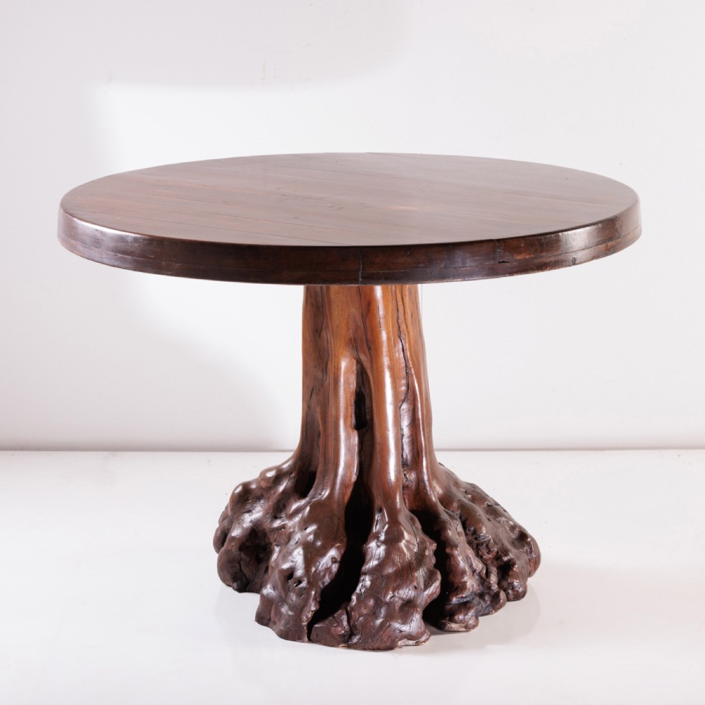 A round olive wood table with a natural tree root pedestal base surrounded by four matching root wood stools. View VIII