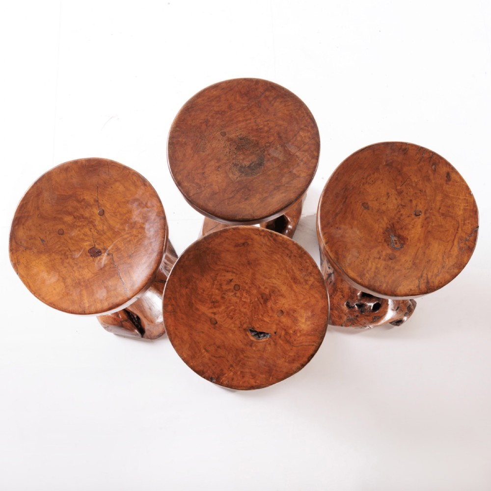 A round olive wood table with a natural tree root pedestal base surrounded by four matching root wood stools. View IX