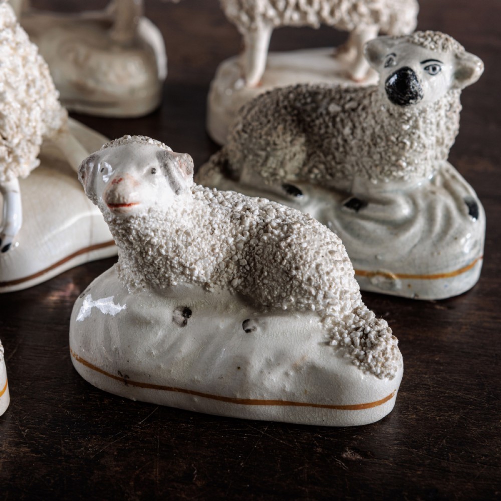 A collection of eight antique 19th-century cream and white ceramic Staffordshire sheep and lamb figurines with textured shredded-clay fleece. View II