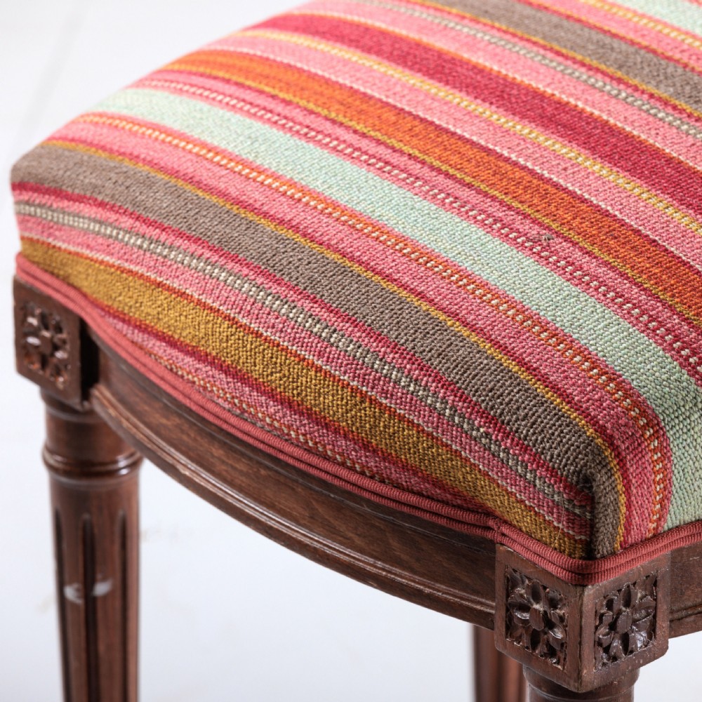 A long nineteenth-century French bench featuring a multi-coloured striped upholstered seat supported by eight fluted dark wood legs with carved rosettes. View IV