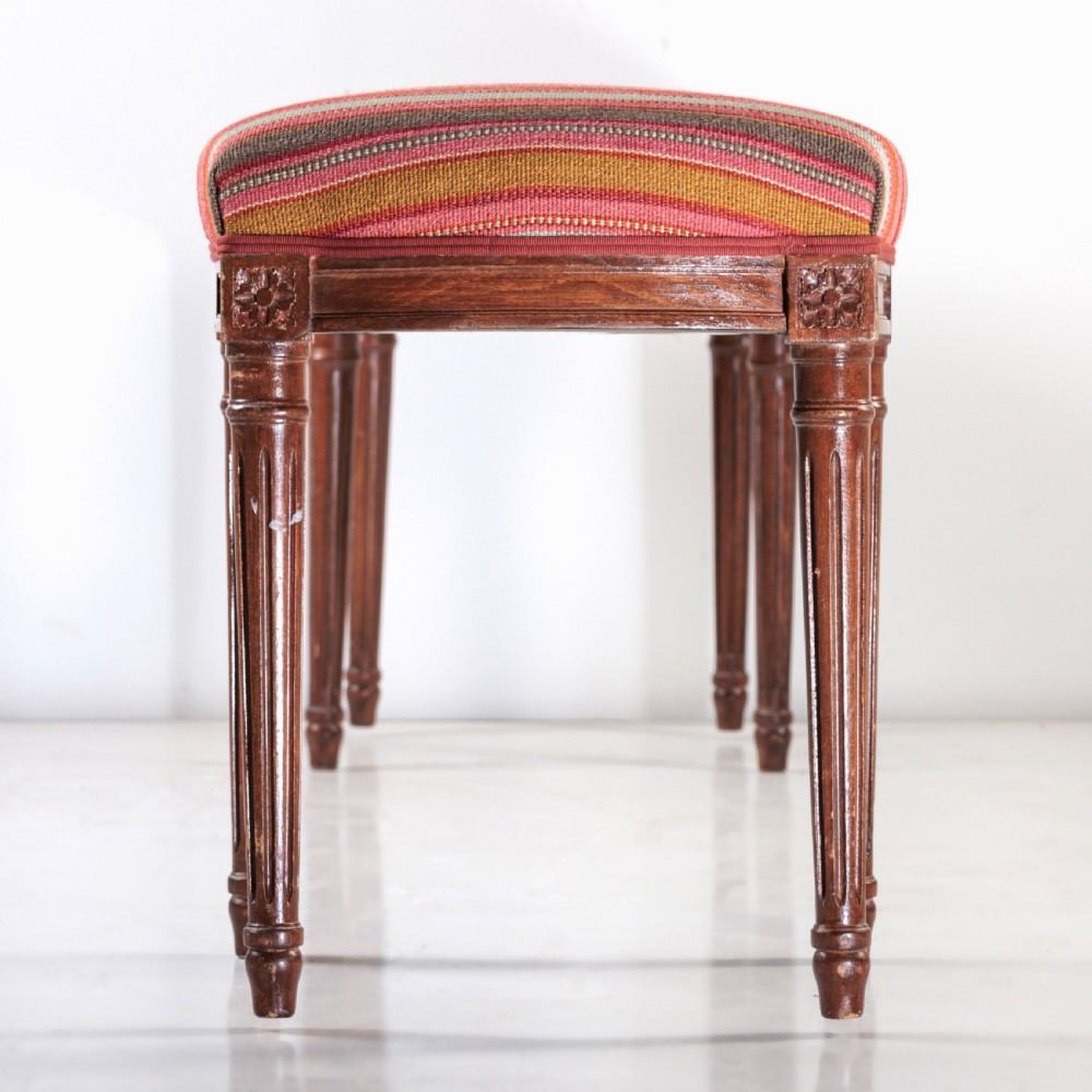 A long nineteenth-century French bench featuring a multi-coloured striped upholstered seat supported by eight fluted dark wood legs with carved rosettes. View VIII
