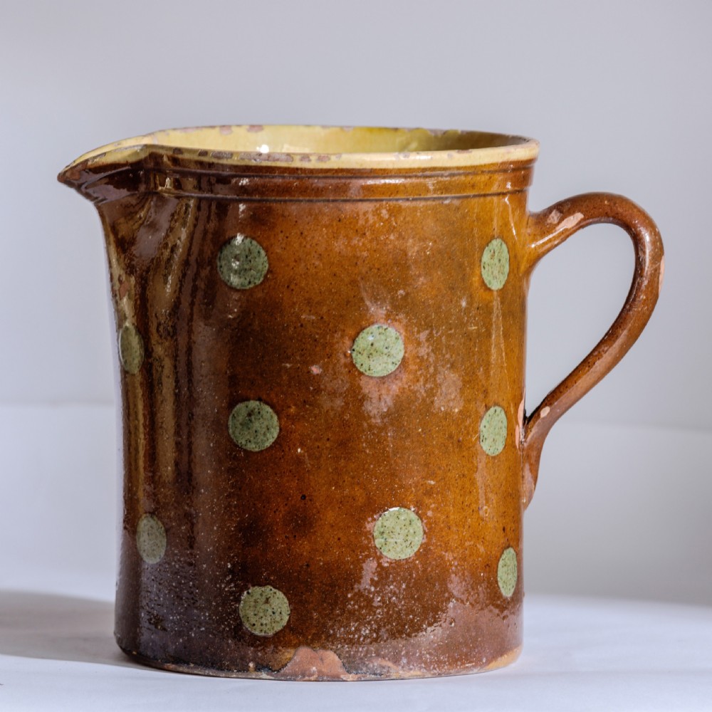 A collection of twelve 19th-century earthenware jugs in varying sizes and colours, each decorated with hand-painted spot and polka dot motifs. View V