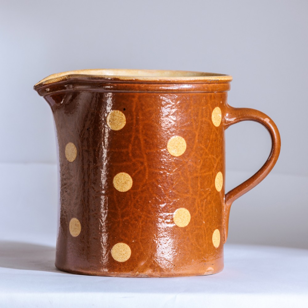 A collection of twelve 19th-century earthenware jugs in varying sizes and colours, each decorated with hand-painted spot and polka dot motifs. View VI