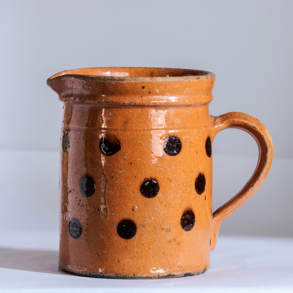 A collection of twelve 19th-century earthenware jugs in varying sizes and colours, each decorated with hand-painted spot and polka dot motifs. View VII