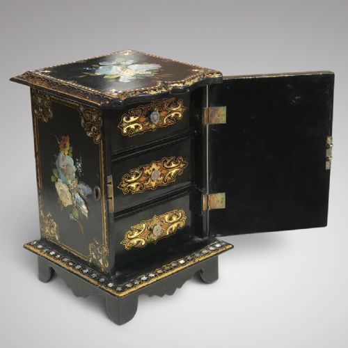fig 1. A Victorian black lacquered papier-mache jewellery cabinet featuring hand-painted floral motifs, mother-of-pearl inlay, and elaborate gold leaf scrolling borders.