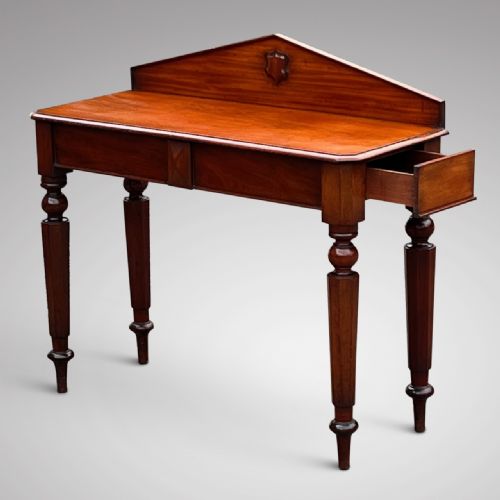 fig 1. A William IV mahogany hall table with turned front legs, a bevelled surface, and a triangular pediment upstand featuring a carved central shield.