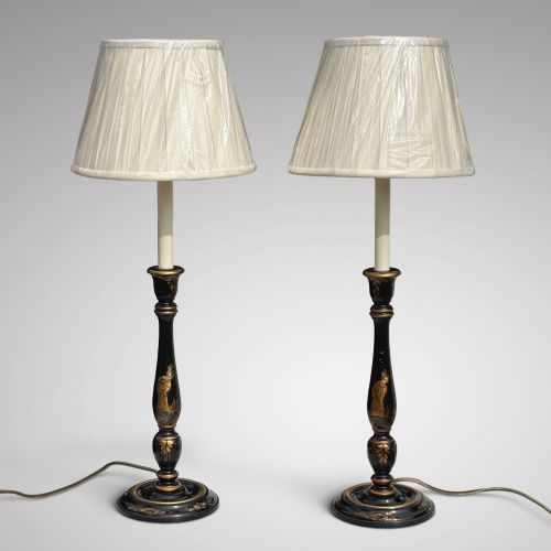 fig 1. A pair of tall black lacquered table lamps decorated with gold Chinoiserie figures, set on circular stepped bases with cream scalloped fabric shades.