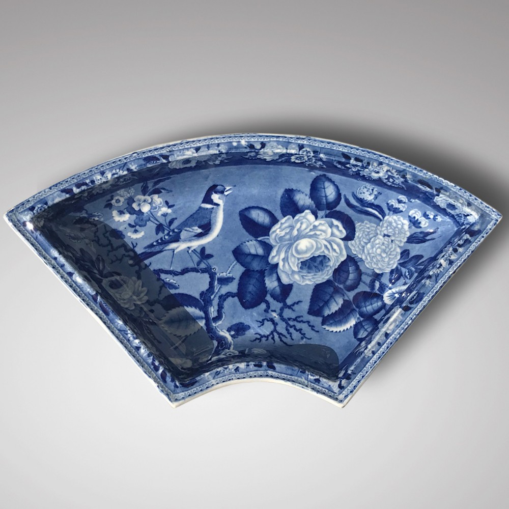 A 19th-century fan-shaped ceramic dish featuring a cobalt blue underglaze print depicting a goldfinch perched among rose blossoms.