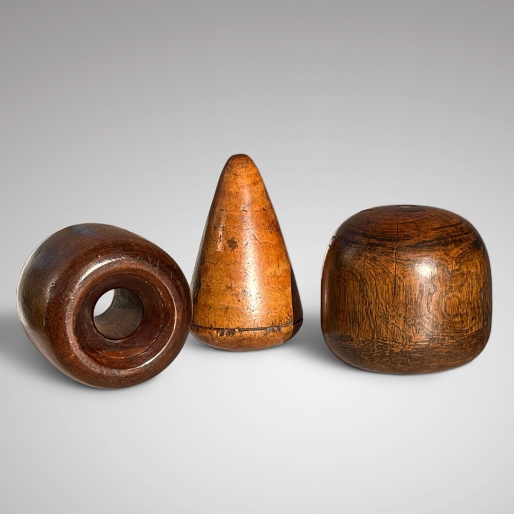 A set of three 19th-century turned wooden plumber tools including a cone, a bobbin, and a rounded dresser block.