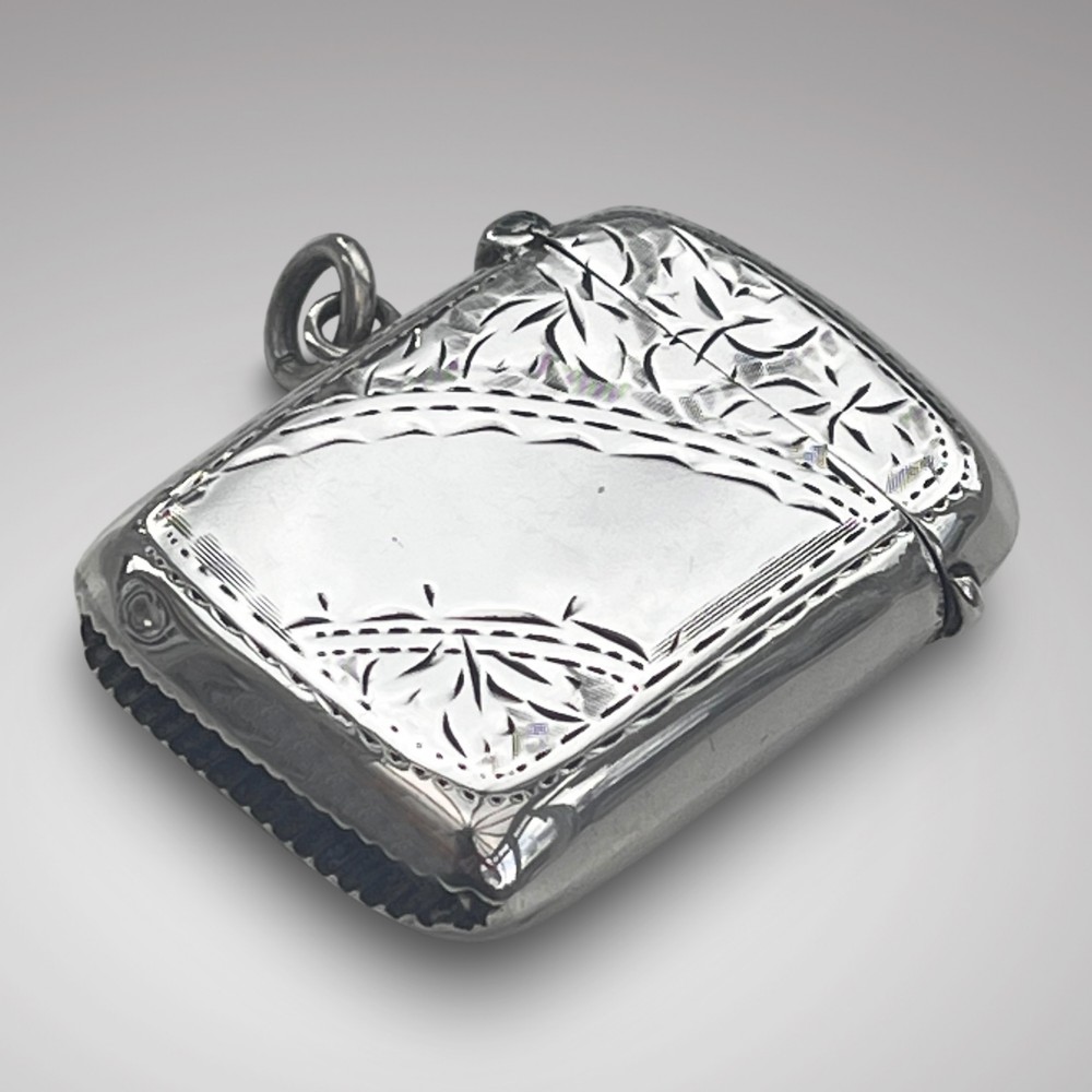 An antique rectangular silver vesta case featuring hand-engraved foliate decoration, a smooth central cartouche, a hinged top lid, and a suspension ring.