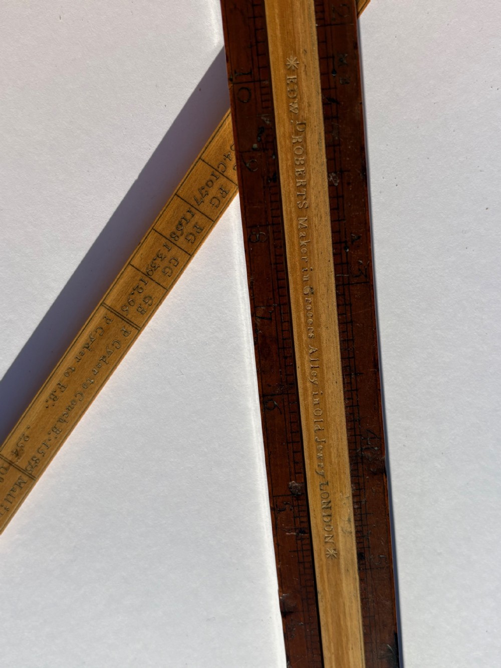 An antique boxwood slide rule featuring etched logarithmic scales and an extended central sliding section on a plain grey background. View VI