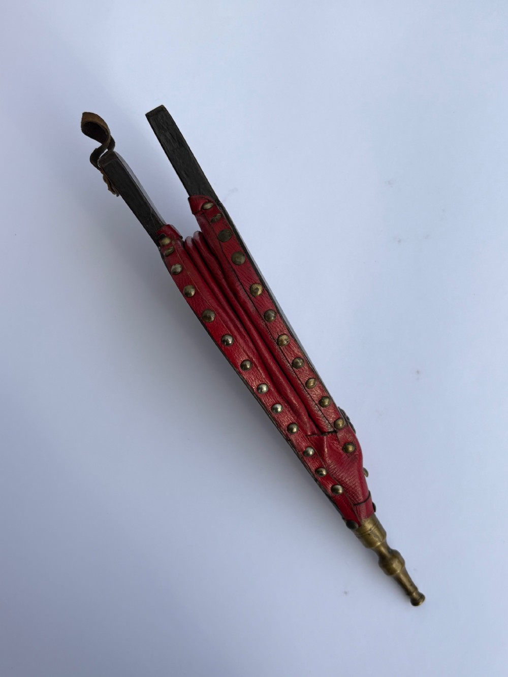 A black lacquered wooden fireplace bellows with gilded Chinoiserie figures, red leather edging secured with brass rivets, and a turned brass nozzle. View IV