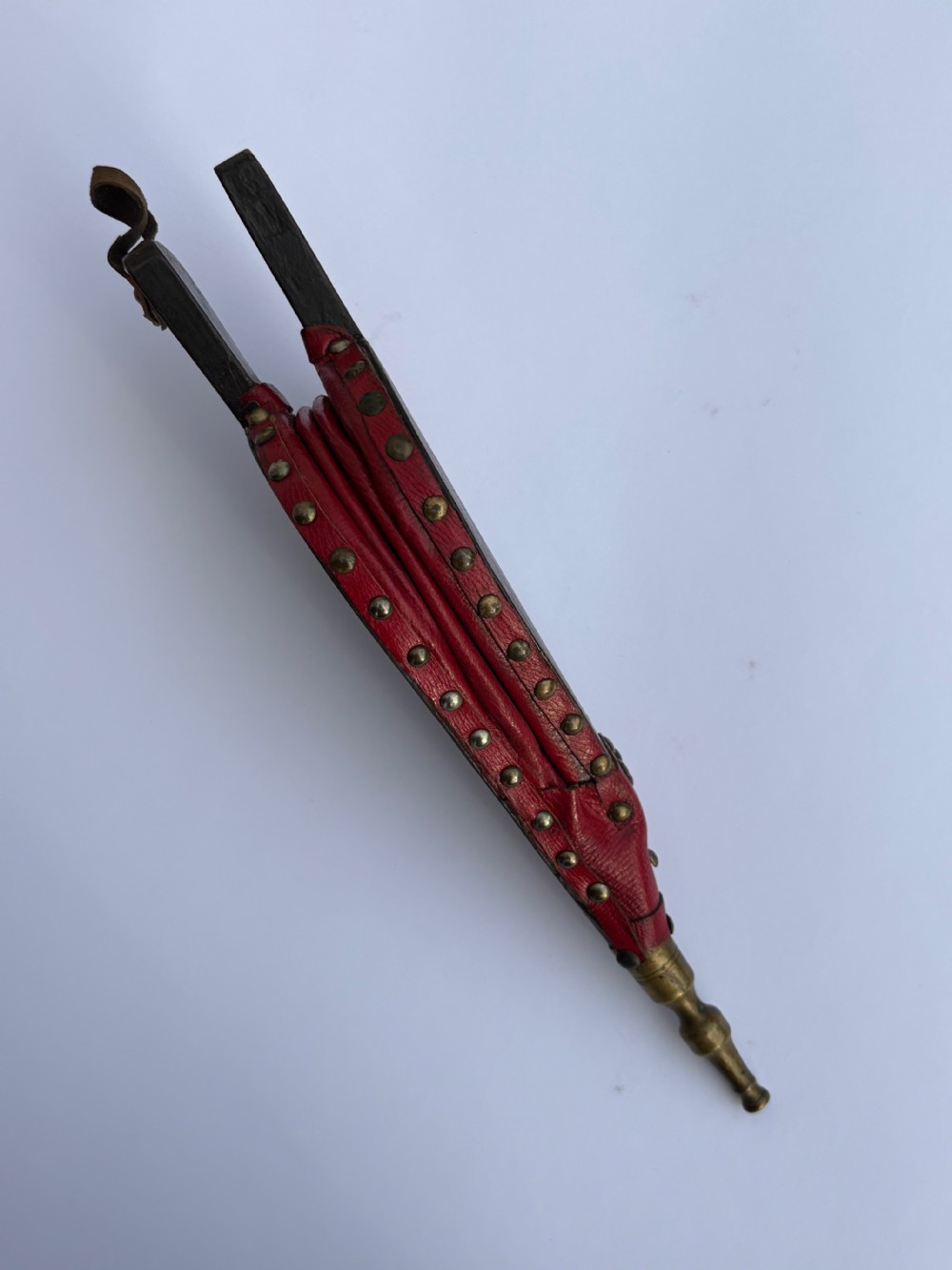 A black lacquered wooden fireplace bellows with gilded Chinoiserie figures, red leather edging secured with brass rivets, and a turned brass nozzle. View V