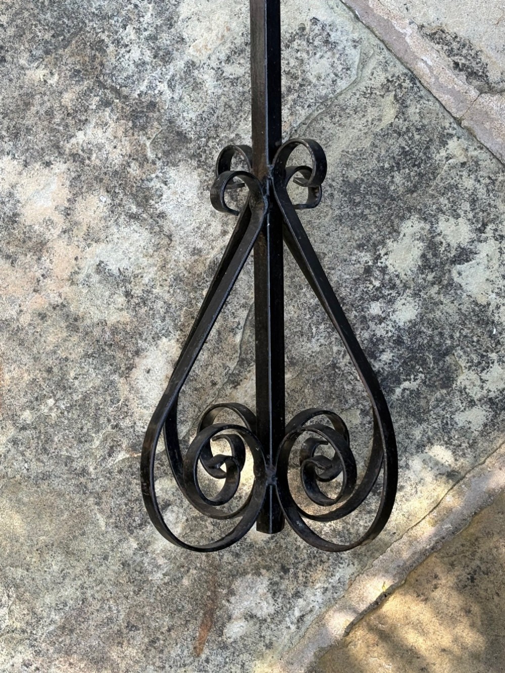 A tall black wrought iron standing sign featuring gold-coloured metal letters spelling WET PAINT framed within a rectangular top section above a scrolled metal base. View II