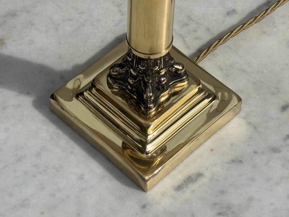 An Edwardian brass table lamp featuring a Corinthian column stem and a pleated cream lampshade decorated with a floral motif. View III