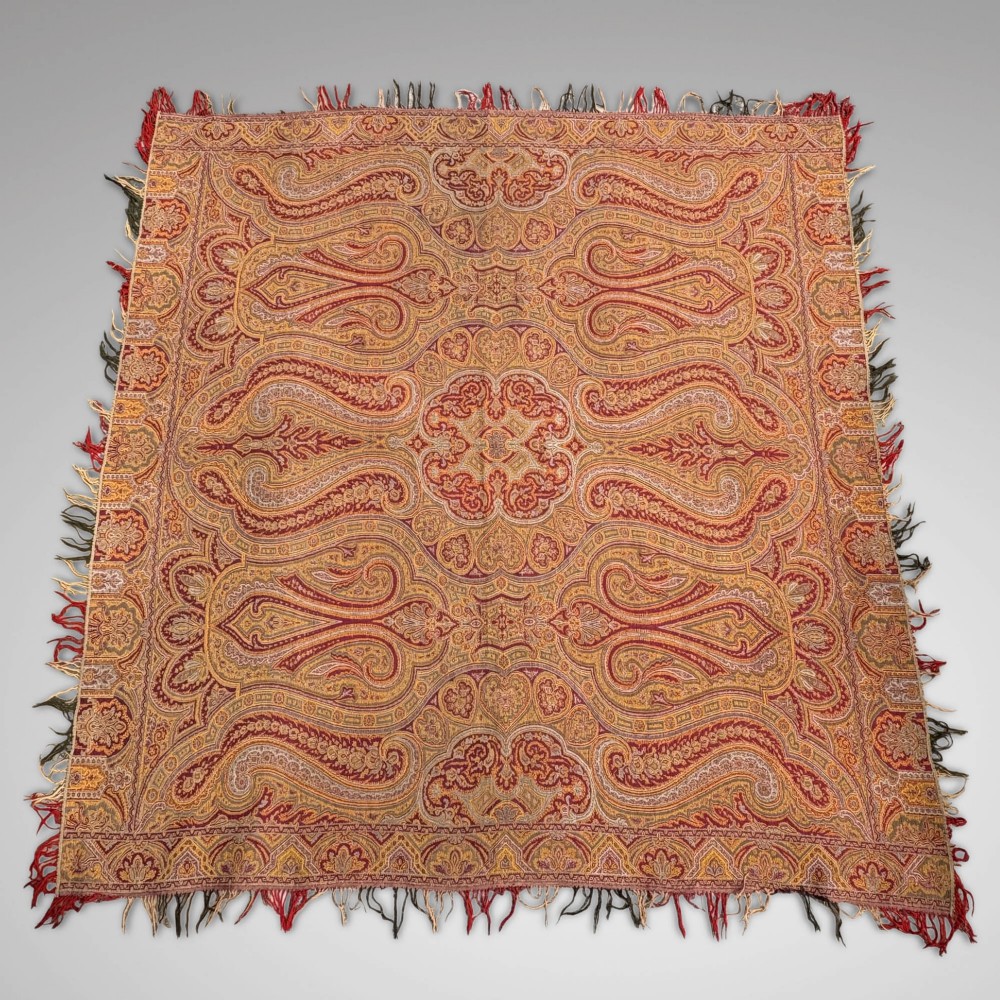 A Victorian wool shawl woven with dense red, ochre, and terracotta paisley motifs, finished with fringed edges. View II