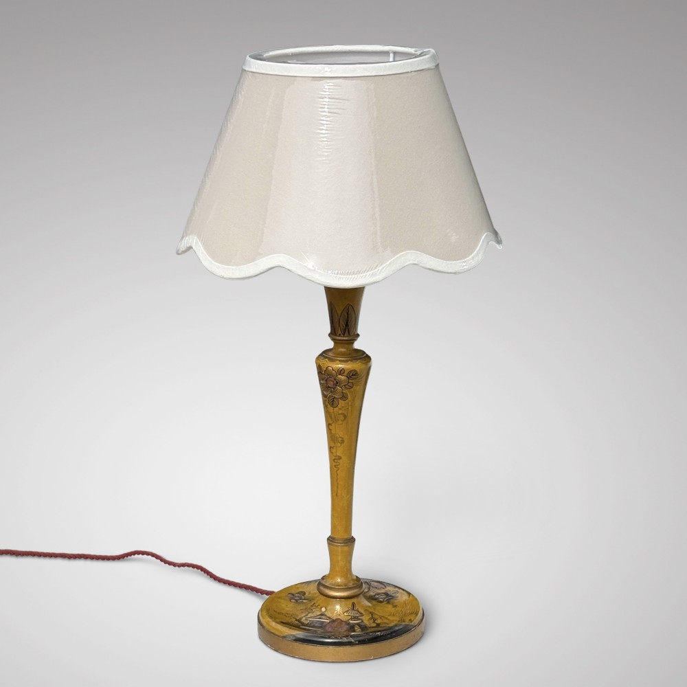 An antique ochre yellow lacquered table lamp featuring hand-painted Chinoiserie motifs and a cream scalloped lampshade.