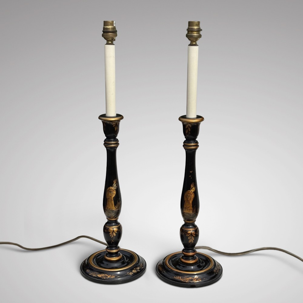 A pair of tall black lacquered table lamps decorated with gold Chinoiserie figures, set on circular stepped bases with cream scalloped fabric shades. View III