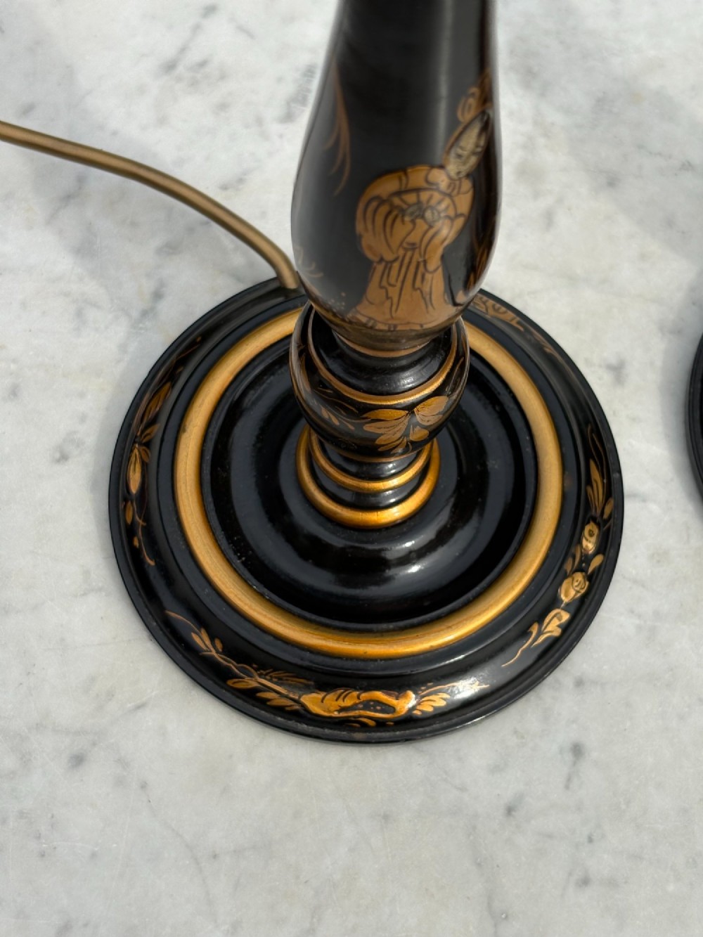 A pair of tall black lacquered table lamps decorated with gold Chinoiserie figures, set on circular stepped bases with cream scalloped fabric shades. View IV