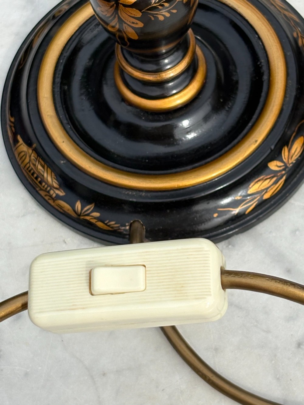 A pair of tall black lacquered table lamps decorated with gold Chinoiserie figures, set on circular stepped bases with cream scalloped fabric shades. View V