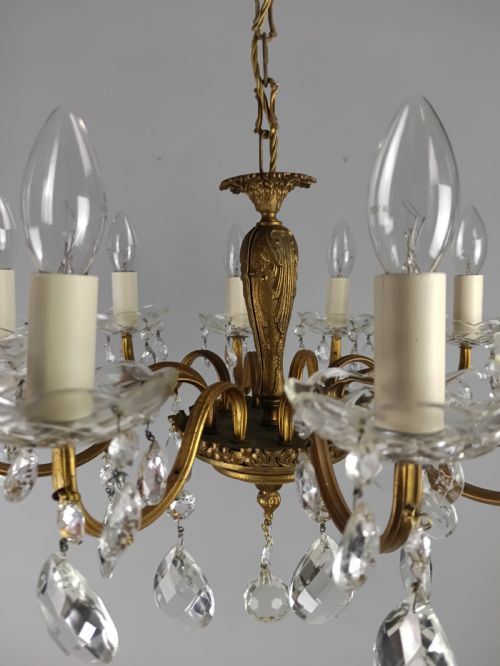 fig 1. A French style gilt brass ten-light chandelier featuring curved candle arms, glass bobeches, and faceted hanging glass drops.