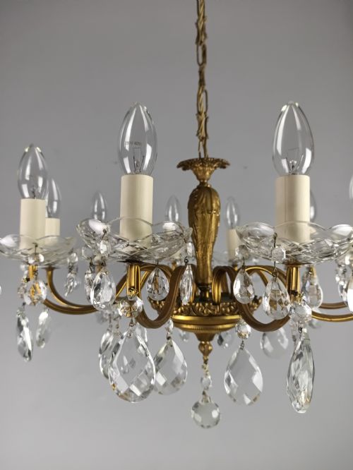 fig 2. A French style gilt brass ten-light chandelier featuring curved candle arms, glass bobeches, and faceted hanging glass drops.