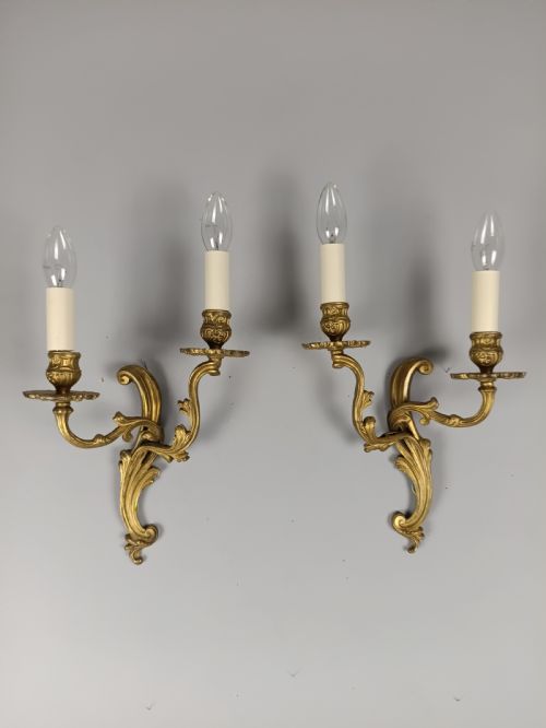 fig 3. A pair of French gilt brass two-arm wall sconces featuring ornate acanthus leaf scrollwork and faux candle sleeve fittings.