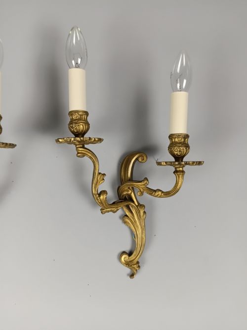 fig 2. A pair of French gilt brass two-arm wall sconces featuring ornate acanthus leaf scrollwork and faux candle sleeve fittings.