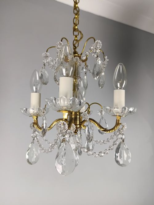 fig 1. A small French brass four-light chandelier adorned with clear cut-crystal droplets, faceted glass swags, and scalloped glass drip pans.