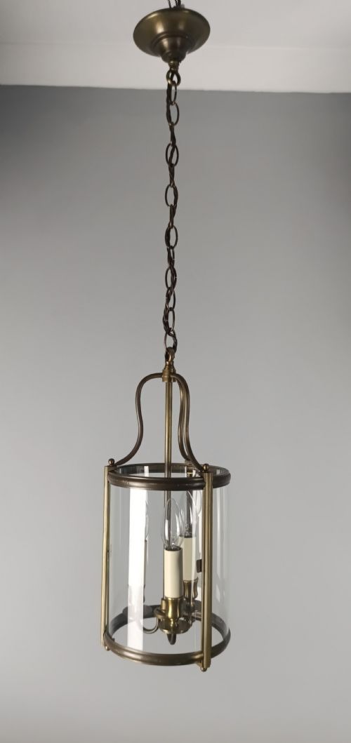 fig 1. A cylindrical gilded brass hall lantern featuring curved clear glass panels and an internal three-light candle cluster.