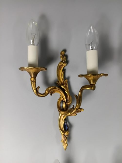 fig 1. Four French Rococo style gilded bronze twin-arm wall lights with foliate scrollwork and white candle sleeves.