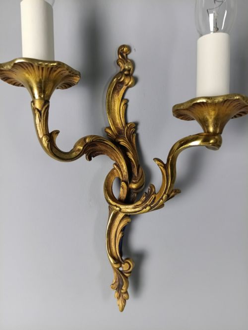 fig 5. Four French Rococo style gilded bronze twin-arm wall lights with foliate scrollwork and white candle sleeves.