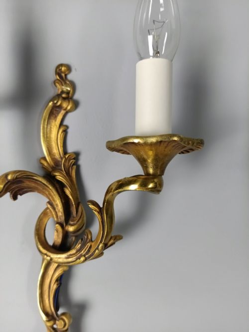 fig 6. Four French Rococo style gilded bronze twin-arm wall lights with foliate scrollwork and white candle sleeves.