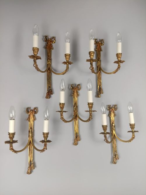 fig 1. A set of five French gilded brass twin-arm wall sconces featuring ribbon bow crests, draped tassel detailing, and candle-style bulb holders.
