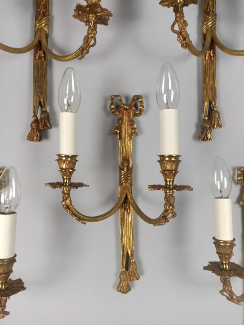 fig 3. A set of five French gilded brass twin-arm wall sconces featuring ribbon bow crests, draped tassel detailing, and candle-style bulb holders.