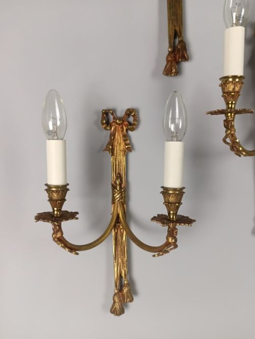 fig 4. A set of five French gilded brass twin-arm wall sconces featuring ribbon bow crests, draped tassel detailing, and candle-style bulb holders.