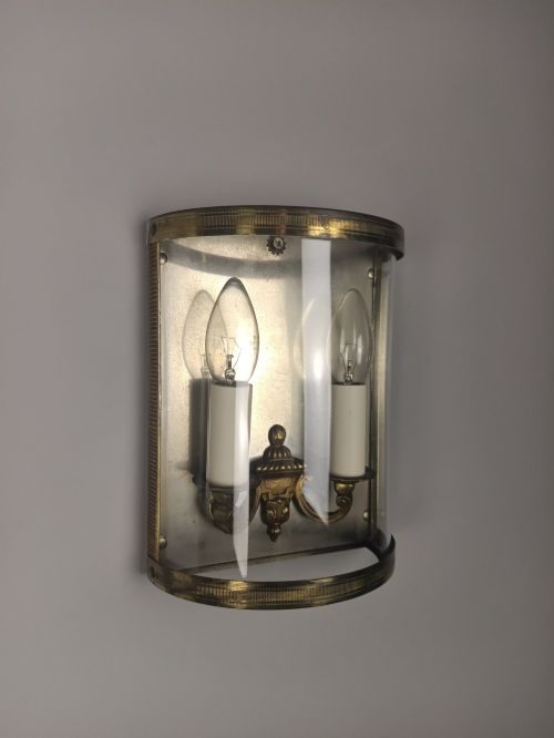 fig 4. A pair of French gilt brass half-lantern wall lights featuring curved clear glass panels and twin candle-style sockets.