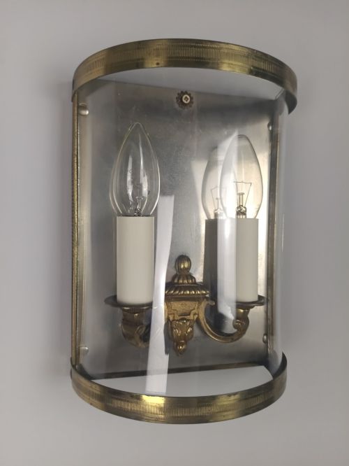 fig 5. A pair of French gilt brass half-lantern wall lights featuring curved clear glass panels and twin candle-style sockets.