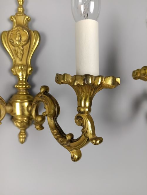 fig 1. A pair of antique French gilded brass wall sconces with twin scrolling arms, central backplates, and candle-style bulb holders.