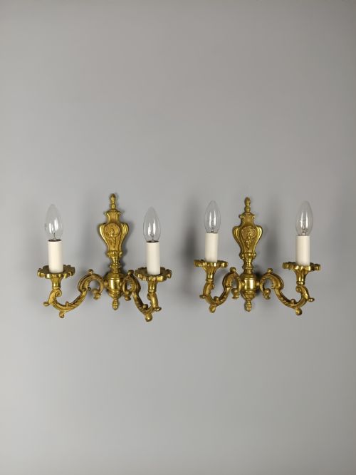 fig 4. A pair of antique French gilded brass wall sconces with twin scrolling arms, central backplates, and candle-style bulb holders.