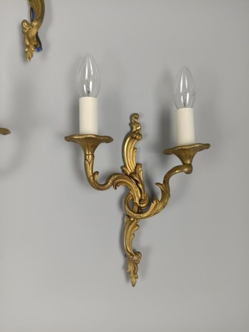fig 3. A set of three French gilded bronze twin-arm wall lights with ornate foliage scrolling and candle-style sockets.