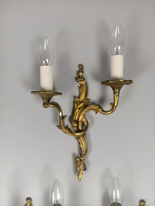 fig 4. A set of three French gilded bronze twin-arm wall lights with ornate foliage scrolling and candle-style sockets.