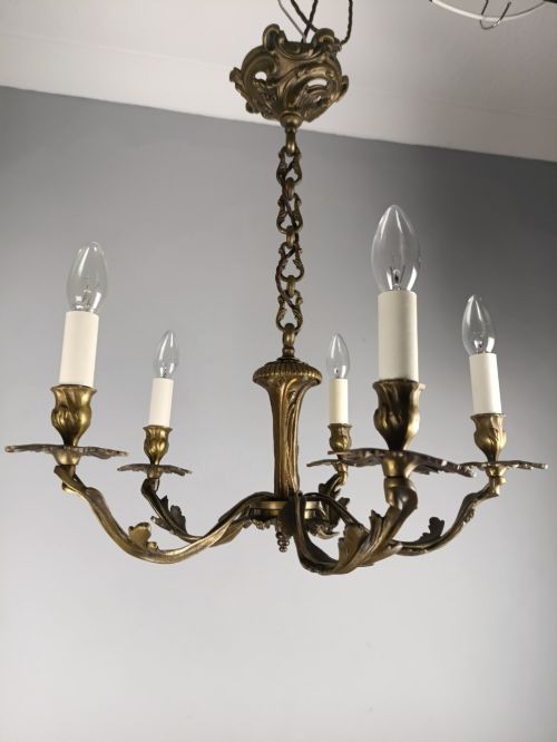 fig 2. A five-arm dark bronze chandelier with cast acanthus leaf arms, white candle sleeves, and a matching hanging chain with ceiling rose.