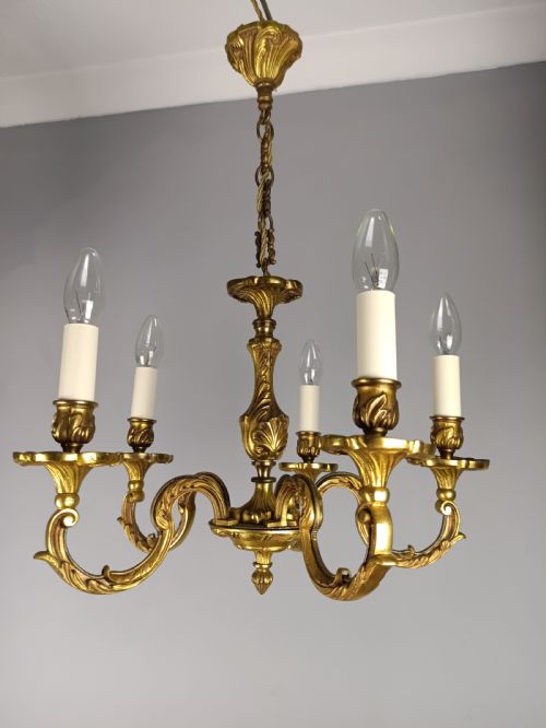 fig 1. A five-arm French gilt bronze chandelier featuring acanthus leaf scroll arms, candle-style sockets, and an ornate central column suspended by a chain.