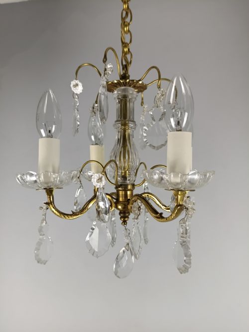 fig 1. A four-arm brass mini chandelier featuring clear glass droplets, floral bobeches, and a central glass stem column.