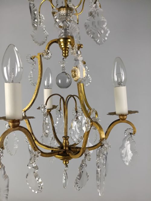 fig 1. A French gilded metal three-arm birdcage chandelier with hanging clear crystal droplets and glass rosette accents.