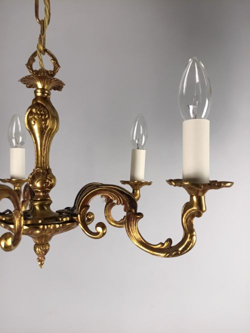 fig 2. A French five-light gilt bronze chandelier featuring scrolling Rococo arms, candle-style bulb holders, and a central chased stem.