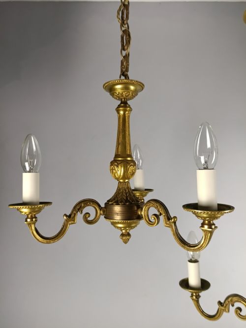 fig 2. A pair of French gilt brass three-arm chandeliers featuring scrolling branches and fluted central columns suspended from metal chains.