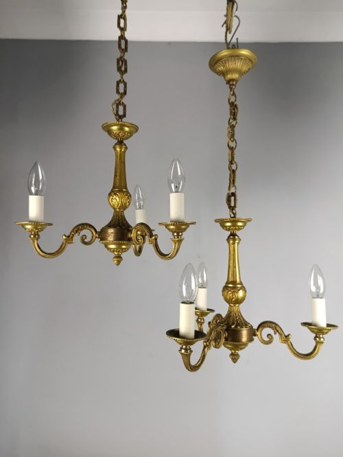 fig 1. A pair of three-arm French gilt brass chandeliers featuring scrolling arms, central baluster shafts, and candle-style sockets.